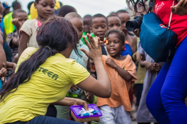 A volunteer interacts with children during an outreach program, engaging with them in a playful manner.