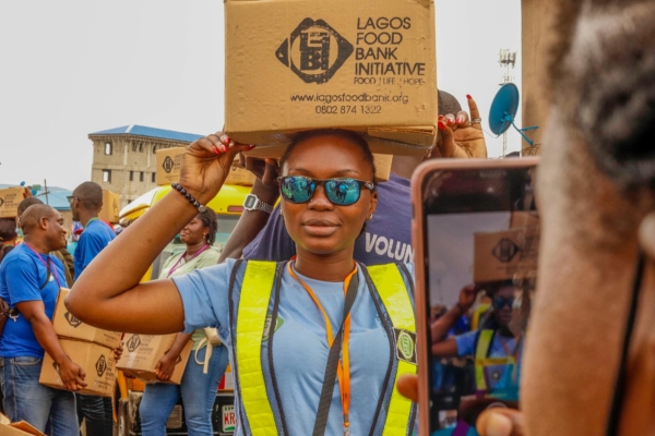 A volunteer carries a box on her head during a food distribution event.