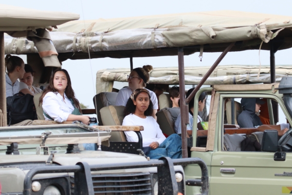 People sit in open safari vehicles, observing the natural surroundings.