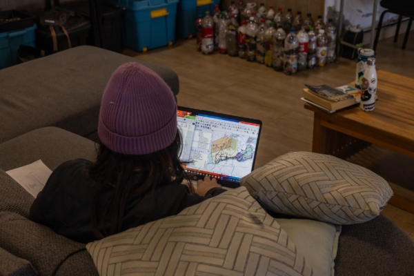 A person wearing a purple beanie analyzing a map on a laptop, likely for field research.