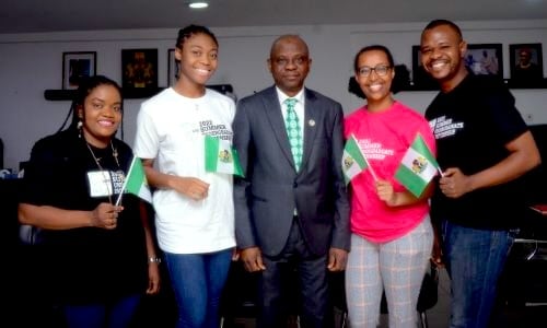 Public health interns with an official holding up Nigerian flags.