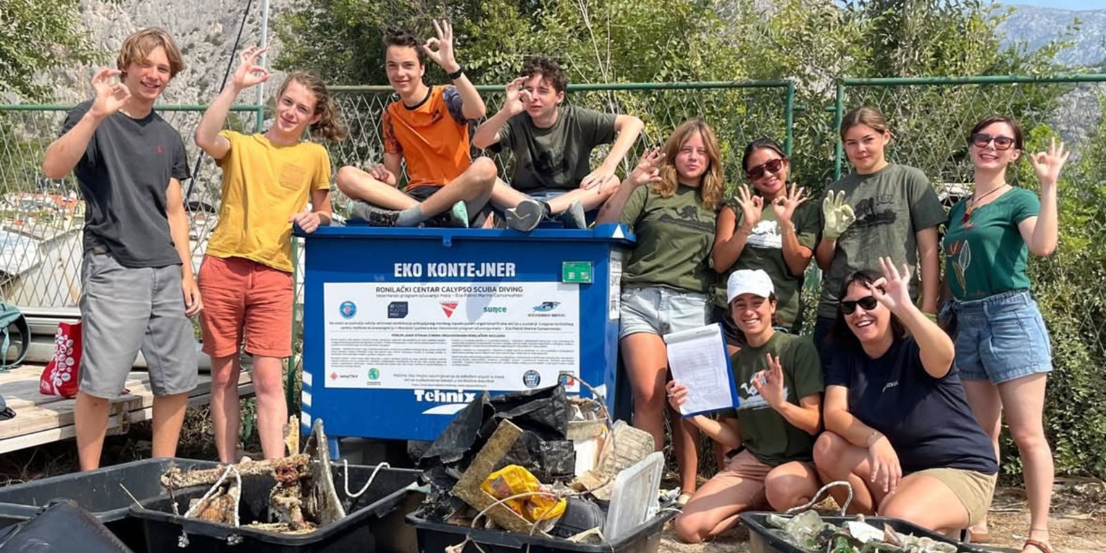 Group of volunteers posing with collected waste in bins and bags