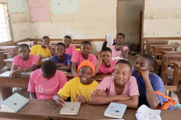 Young girls in B-GILD shirts attentively participate in an online session, highlighting their commitment to tech and digital skills learning.