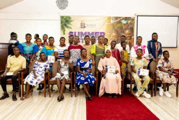 A group of young participants and mentors pose at a **summer program event**, with some holding certificates in a recognition ceremony.