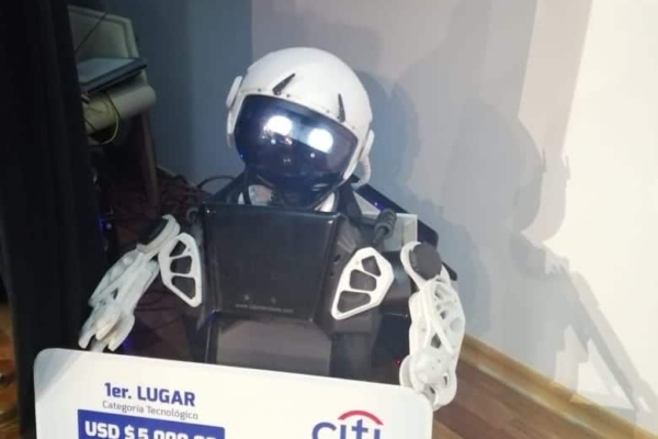 A tiny robot from the robotics internship in Ecuador holding of a cheque.