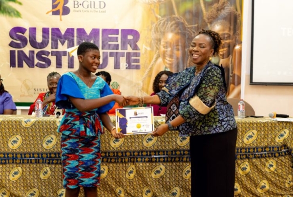 A young participant is awarded a certificate during a B-GILD leadership and mentorship event.