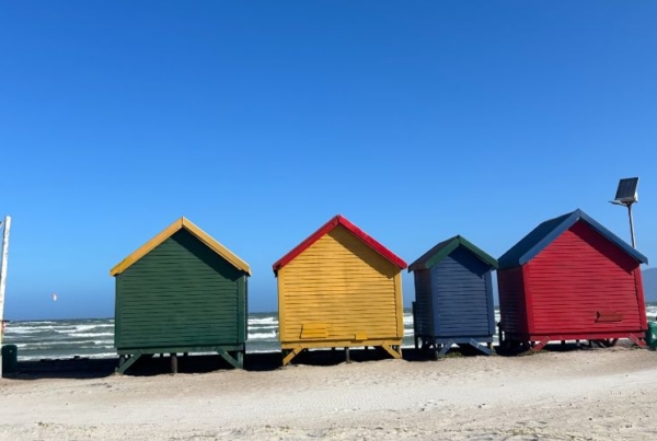 Four little buildings with different color on a beach in Cape Town.