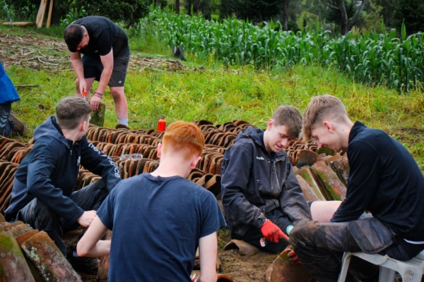 Interns clean and organize traditional clay roofing tiles.