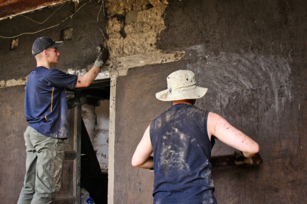 Interns coat a mud wall with a fresh layer of earthen plaster.