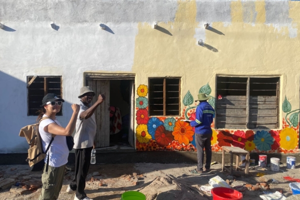 Medical interns posing for a picture while someone is painting a building.