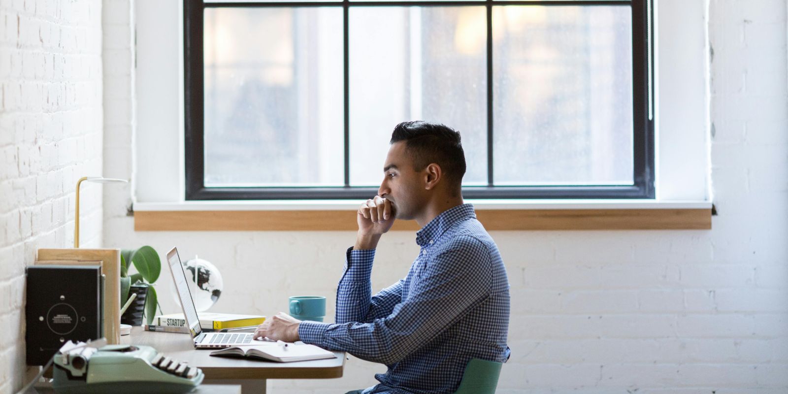 Man using a laptop near a large window
