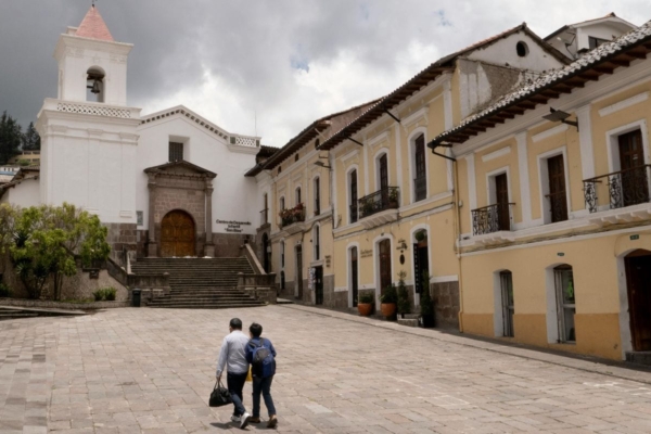 A couple walking around the empty plaza in Quito.