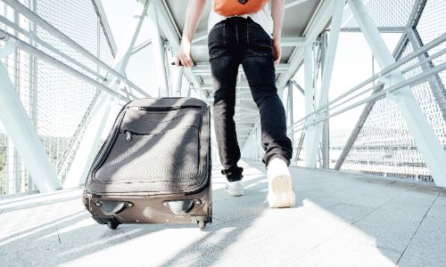 Person walking through an airport bridge pulling a suitcase