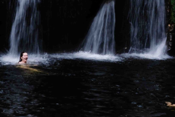 Interns swimming under a rainforest waterfall in Peru.