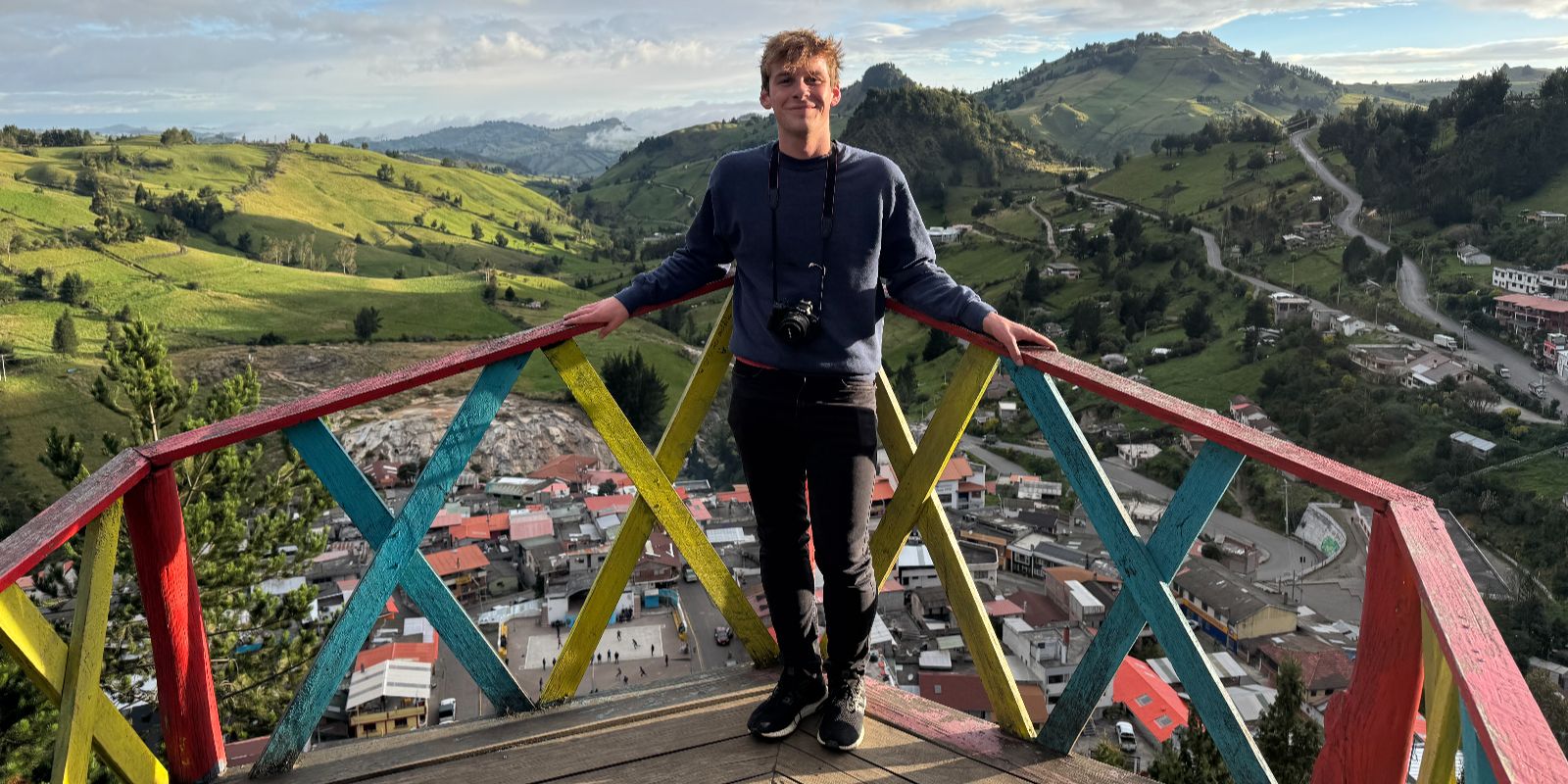 Luke standing on a colorful wooden lookout platform overlooking a rural town