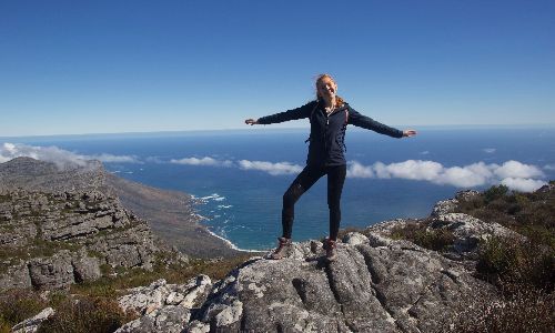 Woman smiling on a mountain peak with the sea in the background