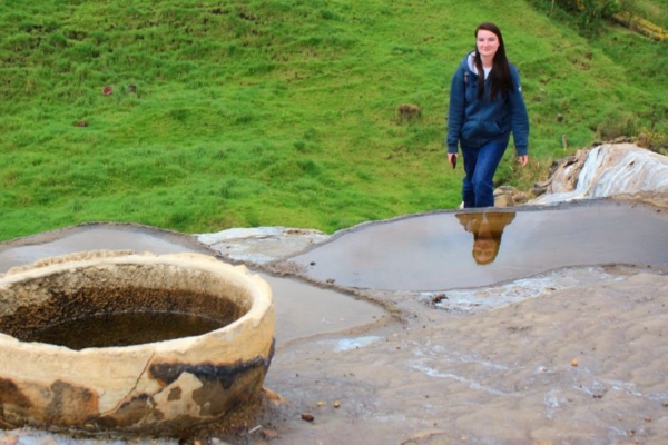 Art Therapy Internship participant walking near natural mineral pools in a rural landscape, connecting environmental exploration with therapeutic learning.