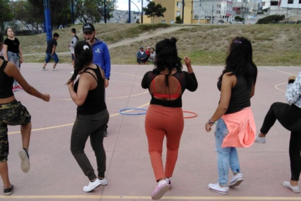 Young women participating in a group movement or dance activity on an outdoor court during a young womens health internship.