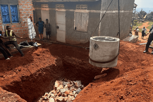 A group of people moving a large pipe into a hole in the ground.