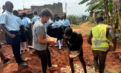 A large group of adults and students moving rocks.