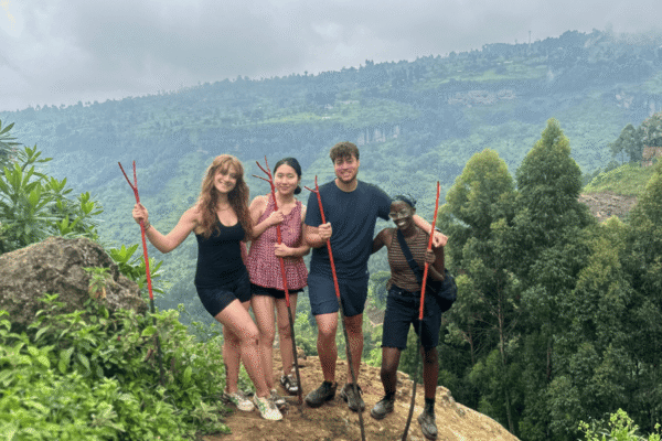Four people holding sticks standing on a cliff.