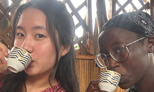 Two women sipping out of small cups.