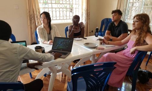 Several people sitting around a table looking at something off-camera.