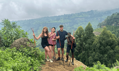 Four people holding sticks standing on a cliff.