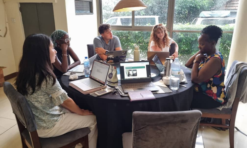 A group of five people sitting around a table working on laptops.
