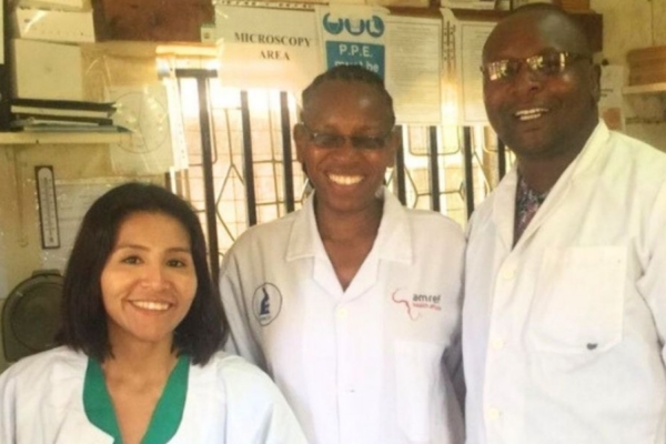 Three smiling people wearing white lab coats.