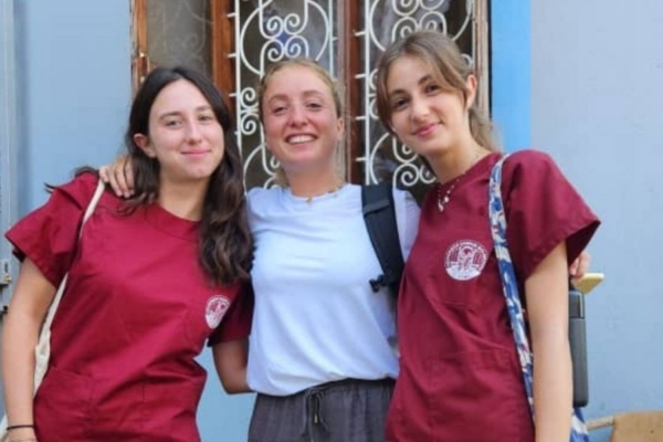 Three smiling women with their arms around one another.
