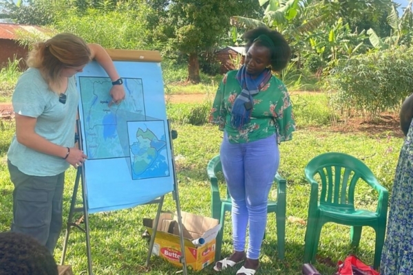 An intern and staff members pointing to a map on an easel outside.