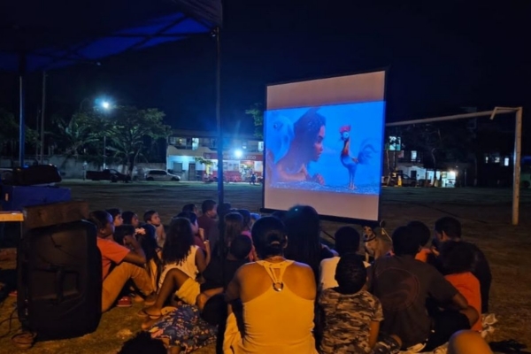 A group of children watchin an animated movie outside.