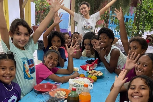 Intern posing next to a table surrounded by children.