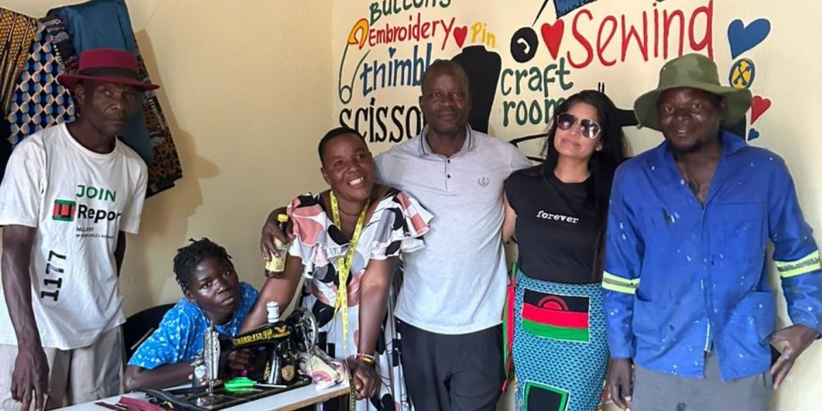 A group of people posing in front of a mural in Malawi.