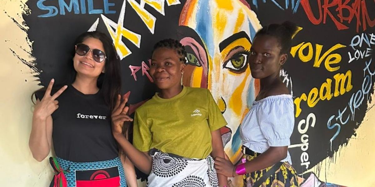 Three women posing in front of a mural.