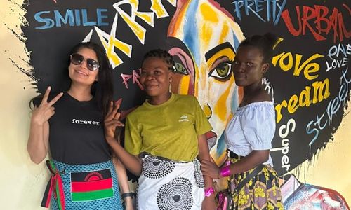Three women posing in front of a mural.